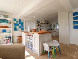 A kitchen with an island wooden countertop a small round table with two children's chairs and blue artwork on the walls at The Old Harbour Masters House in Fowey