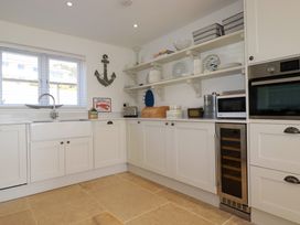 A kitchen with white cabinets open shelves appliances and a window at The Old Harbour Masters House in Fowey