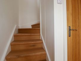 Wooden staircase next to a closed wooden door with a metal handle and white walls at The Old Harbour Masters House in Fowey