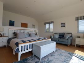 A bedroom with a bed a chest two nightstands a sofa two windows and a rug at The Old Harbour Masters House in Fowey