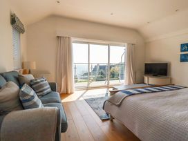 A bedroom with a bed a sofa a television and large sliding glass doors overlooking the sea at The Old Harbour Masters House in Fowey