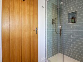 A shower with glass doors and blue tiled walls next to a wooden door at The Old Harbour Masters House in Fowey