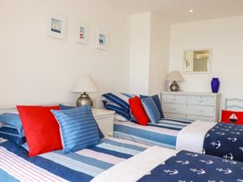 A bedroom with two single beds striped bedding and red and blue cushions at The Old Harbour Masters House in Fowey