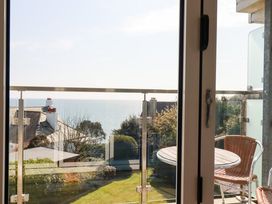 A balcony with table and chairs overlooking garden and sea at The Old Harbour Masters House in Fowey