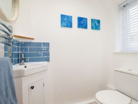 A bathroom with a white sink cabinet blue tiled backsplash a toilet and three blue paintings on the wall at The Old Harbour Masters House in Fowey