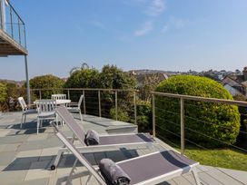 An outdoor patio with two lounge chairs with towels and a table with four chairs surrounded by greenery at The Old Harbour Masters House in Fowey