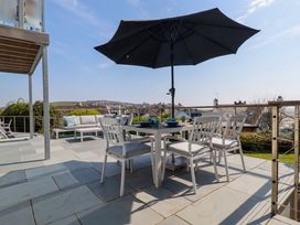 An outdoor patio with a table and chairs under a large umbrella and a sofa with cushions at The Old Harbour Masters House in Fowey