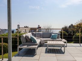 An outdoor patio with a sectional sofa and a coffee table overlooking rooftops and the sea at The Old Harbour Masters House in Fowey