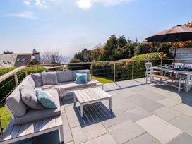 An outdoor patio with a sectional sofa a coffee table and a dining table with chairs and an umbrella at The Old Harbour Masters House in Fowey