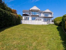 A large house with balconies and outdoor furniture overlooking a grassy lawn with hedges at The Old Harbour Masters House in Fowey
