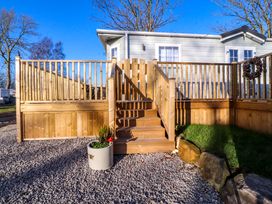 Wooden steps leading to a raised deck with railings attached to a light gray mobile home near trees at 2 Willow Way near Lytham
