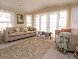 A living room with two sofas a carpet bench with throws and large windows at 2 Willow Way near Lytham