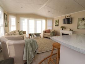 A living room with sofas a television and a countertop with stools at 2 Willow Way near Lytham