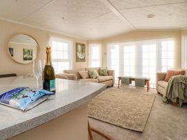 A living room with beige sofas a patterned rug and a countertop with a bottle of prosecco and two glasses at 2 Willow Way near Lytham
