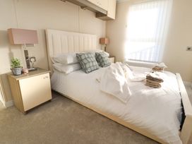 A bedroom with a bed with white bedding and pillows and bedside tables with lamps at 2 Willow Way near Lytham