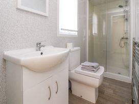 A bathroom with a white sink cabinet a toilet with folded towels and a glass shower enclosure at 2 Willow Way near Lytham