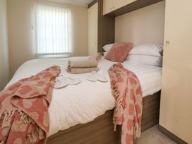 A bedroom with a double bed towels slippers and blankets at 2 Willow Way near Lytham
