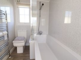 A bathroom with a bathtub a shower a toilet a towel rack and a window at 2 Willow Way near Lytham