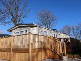 A mobile home with a wooden deck and railing surrounded by leafless trees at 2 Willow Way near Lytham