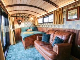 A room with a bed and brown leather sofa with blue pillows at GWR Wagon - Victoria Station in Ludlow