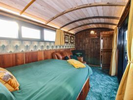 A bedroom with a green bedspread a leather sofa wooden walls and ceiling at GWR Wagon - Victoria Station in Ludlow