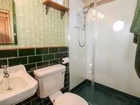 A bathroom with a white toilet sink shower and green tiled walls at GWR Wagon - Victoria Station in Ludlow