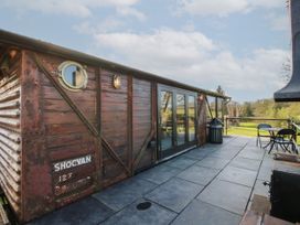 An outdoor patio area with a vintage wooden train carriage converted into a building at GWR Wagon - Victoria Station in Ludlow