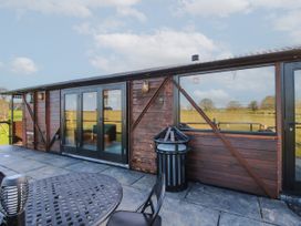 An outdoor patio area with a round metal table and chairs next to a wooden building with large windows and glass doors at GWR Wagon Victoria Station Ludlow