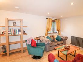 A living room with a sofa, armchairs, a wooden coffee table, and a bookshelf at Orchard Retreat Staycation in Kirton