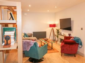 A living room with armchairs a coffee table a TV on the wall and a bookshelf at Orchard Retreat Staycation in Kirton