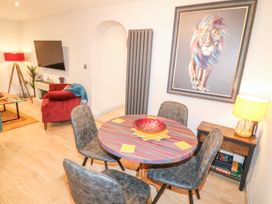 A dining area with a round table and four chairs a framed lion painting on the wall and a side table with a lamp and board games at Orchard Retreat Staycation in Kirton