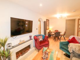 A living room with a mounted TV electric fireplace two armchairs a wooden coffee table and a dining table with four chairs at Orchard Retreat Staycation in Kirton