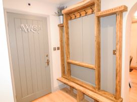 A hallway with a grey door marked WC and a wooden coat rack with hooks and a bench at Orchard Retreat Staycation in Kirton