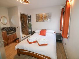 A bedroom with a double bed with towels placed on it a bedside table a shower area and a wash basin at Orchard Retreat Staycation in Kirton
