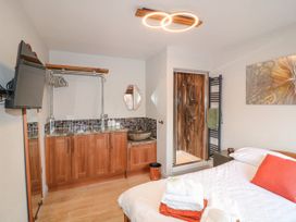 A bedroom with a wooden cabinet, a glass vessel sink, a walk-in shower, a wall-mounted TV, and a bed with towels and orange pillow at Orchard Retreat Staycation in Kirton
