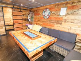 A room with wooden walls a sliding barn door a sectional sofa and a wooden table with a glass centerpiece at Orchard Retreat Staycation in Kirton