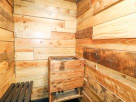 A small wooden room with a wooden heater containing sauna stones and a wooden bench at Orchard Retreat Staycation Kirton