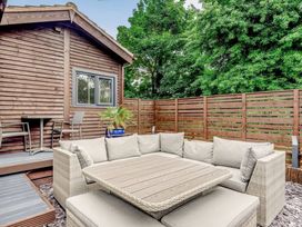 An outdoor seating area with beige cushions a wooden table a wooden fence and a wooden building with chairs and a small table at Orchard Retreat Staycation in Kirton