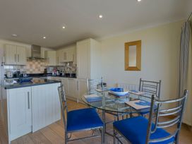 A kitchen with a dining area featuring a glass table and chairs at Apartment 12, Burgh Island Causeway Bigbury-On-Sea