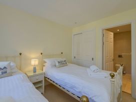 A bedroom with twin beds and a bathroom door at Apartment 12, Burgh Island Causeway in Bigbury-On-Sea