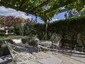 A garden with chairs and a table under a grapevine at Heathcliffe House in Caslteton near Cardiff