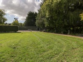 An outdoor area with a tennis court and grass at Heathcliffe House in Castleton near Cardiff