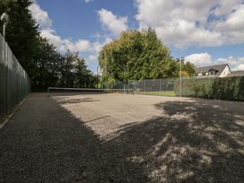 A tennis court with a net and surrounding fence at Heathcliffe House Caslteton near Cardiff