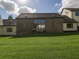 An outdoor view of a stone building with windows and a green lawn at Heathcliffe House, Castleton near Cardiff