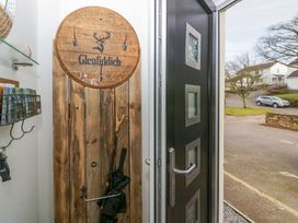 A hallway with a wooden Glenfiddich coat rack umbrella stand and a black door leading outside at Flat 6 Aikbank in Whitehaven
