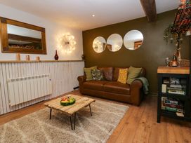 A living room with a brown leather sofa cushions a wooden coffee table with fruit and mirrors on the wall at Flat 6 Aikbank in Whitehaven