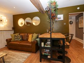 A living room with a brown leather sofa and a wooden table with chairs at Flat 6 Aikbank in Whitehaven
