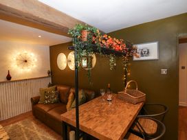 A living area with a brown leather sofa and wooden table with chairs and plants at Flat 6 Aikbank in Whitehaven