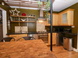 A kitchen with wooden cabinets a stainless steel oven sink and shelves with decor at Flat 6 Aikbank in Whitehaven