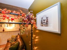 A living area with a brown leather sofa green cushions framed animal artwork and string lights at Flat 6 Aikbank in Whitehaven